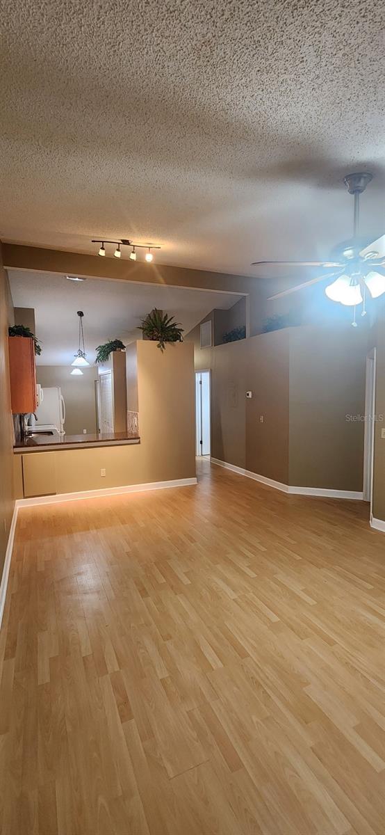 spare room with light hardwood / wood-style flooring, a textured ceiling, and ceiling fan