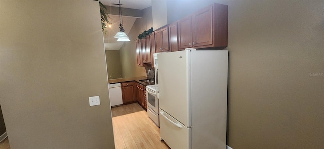 kitchen with white appliances, sink, hanging light fixtures, light hardwood / wood-style floors, and vaulted ceiling