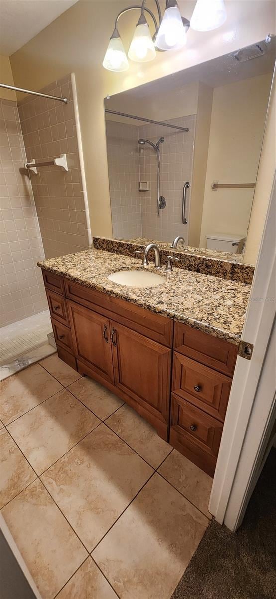 bathroom with vanity, tile patterned flooring, toilet, and tiled shower