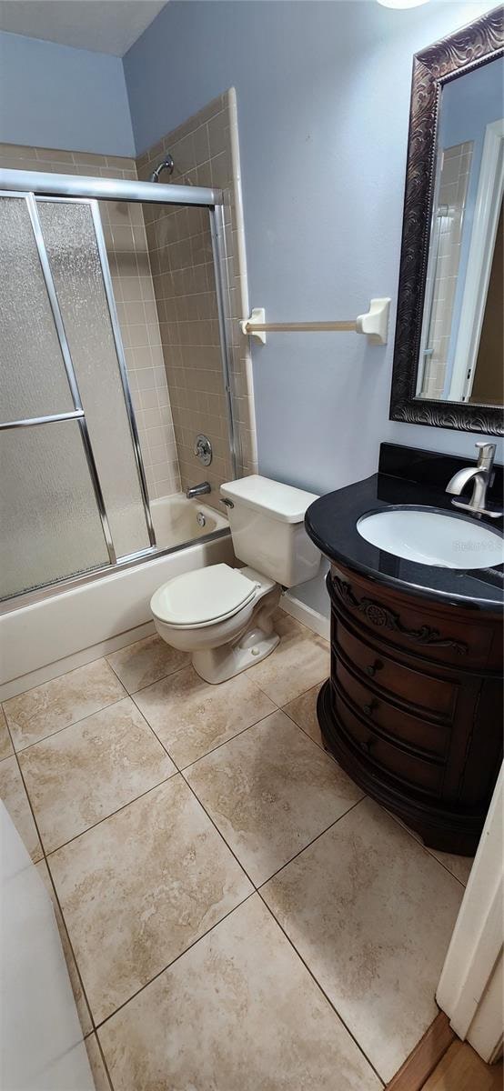 full bathroom featuring vanity, enclosed tub / shower combo, toilet, and tile patterned flooring