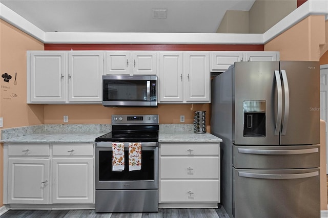 kitchen with white cabinets, stainless steel appliances, light stone counters, and dark wood-type flooring