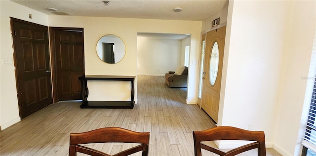 corridor with a textured ceiling and light hardwood / wood-style flooring