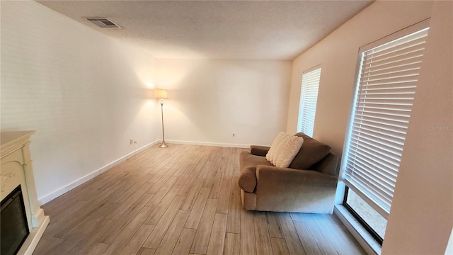 living room featuring light hardwood / wood-style flooring, a textured ceiling, and plenty of natural light