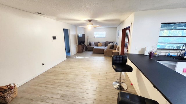 interior space with ceiling fan, a textured ceiling, and light hardwood / wood-style flooring