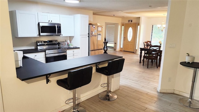 kitchen featuring a breakfast bar, white cabinets, appliances with stainless steel finishes, and light wood-type flooring