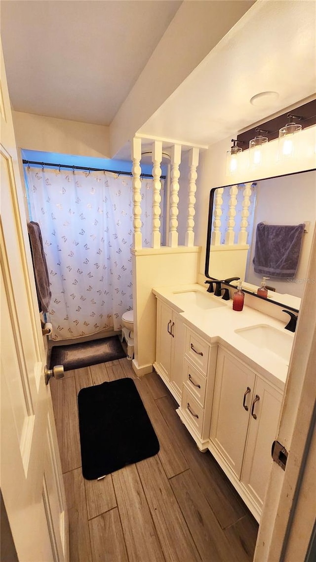 bathroom with wood-type flooring, a shower with curtain, vanity, and toilet