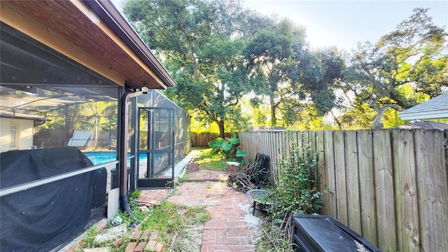 view of yard featuring a fenced in pool, glass enclosure, and a patio