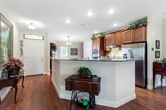 kitchen with dark stone countertops, a center island, dark hardwood / wood-style flooring, and stainless steel appliances