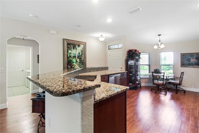 kitchen featuring dishwasher, dark hardwood / wood-style flooring, stone counters, decorative light fixtures, and a spacious island