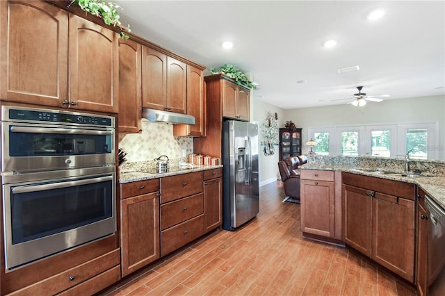 kitchen with ceiling fan, light stone counters, sink, light hardwood / wood-style flooring, and appliances with stainless steel finishes