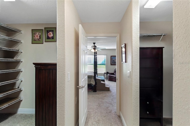 hall with light carpet and a textured ceiling