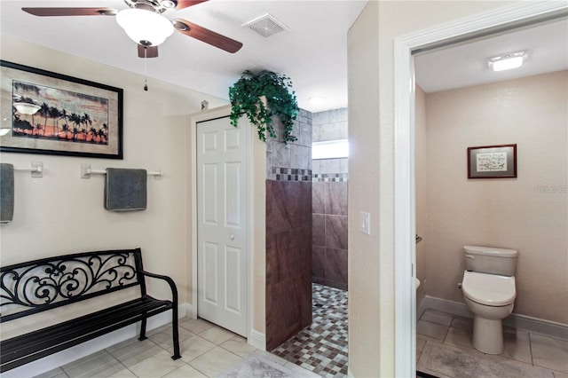 bathroom featuring a tile shower, tile patterned flooring, toilet, and ceiling fan