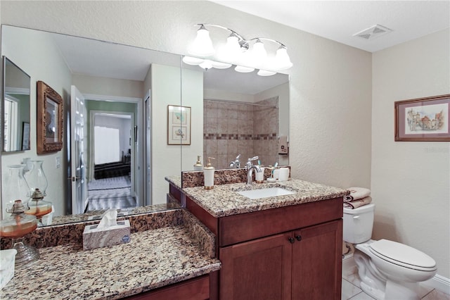 bathroom with tile patterned flooring, a textured ceiling, tiled shower, vanity, and toilet