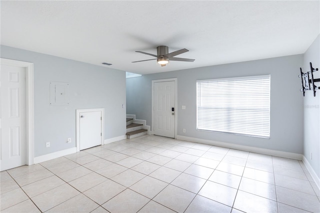 tiled empty room featuring electric panel and ceiling fan