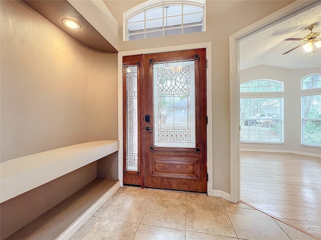 entryway featuring lofted ceiling, ceiling fan, a textured ceiling, and light tile patterned floors