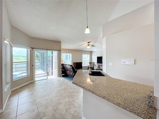 kitchen featuring a textured ceiling, ceiling fan, sink, and pendant lighting