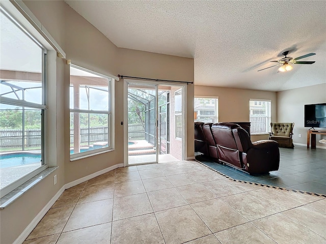 living room featuring ceiling fan, a healthy amount of sunlight, a textured ceiling, and light tile patterned floors