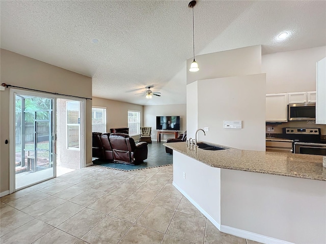 kitchen with white cabinets, light stone counters, appliances with stainless steel finishes, and hanging light fixtures