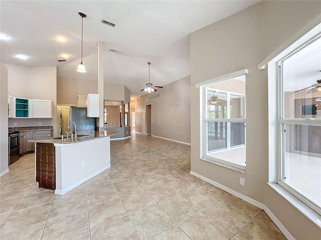 kitchen featuring hanging light fixtures, stainless steel appliances, white cabinets, dark stone countertops, and high vaulted ceiling