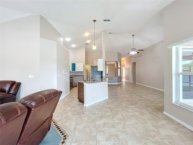 kitchen with sink, hanging light fixtures, ceiling fan, dark stone countertops, and high vaulted ceiling