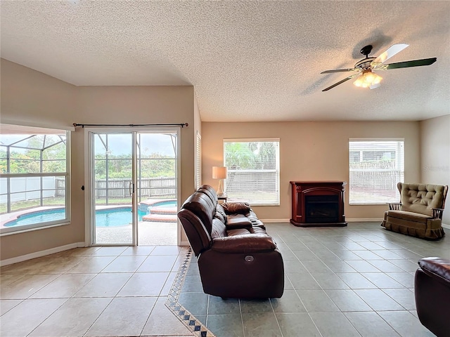 living room featuring a textured ceiling, ceiling fan, light tile patterned flooring, and a wealth of natural light