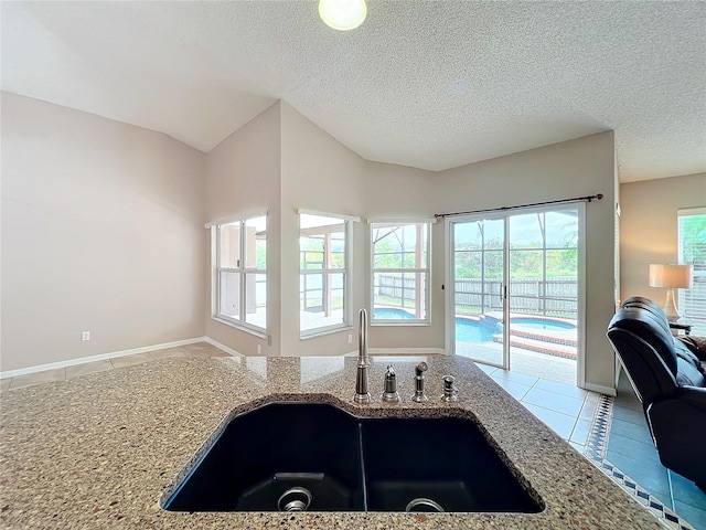 kitchen with lofted ceiling, a textured ceiling, sink, and plenty of natural light