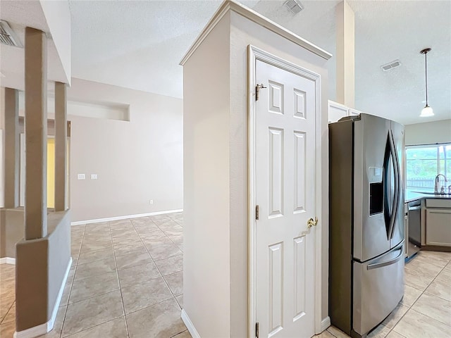 kitchen with a textured ceiling, light tile patterned flooring, and stainless steel appliances