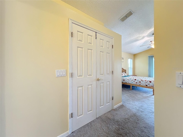 hall featuring vaulted ceiling, carpet flooring, and a textured ceiling