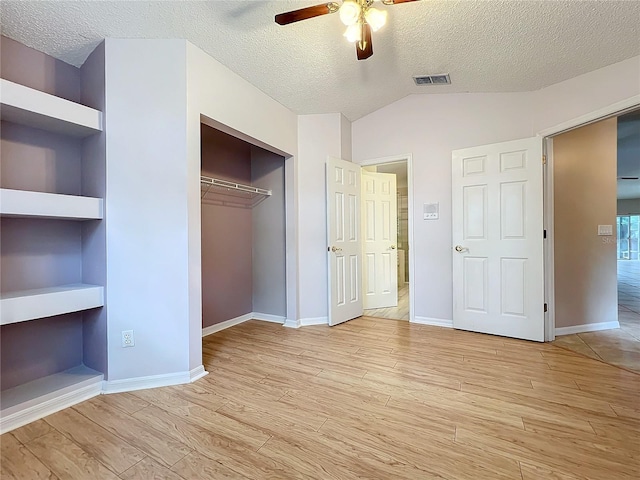 unfurnished bedroom featuring a closet, vaulted ceiling, a textured ceiling, light hardwood / wood-style floors, and ceiling fan