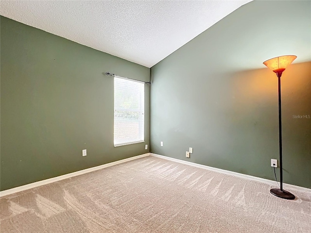 carpeted empty room featuring a textured ceiling and vaulted ceiling