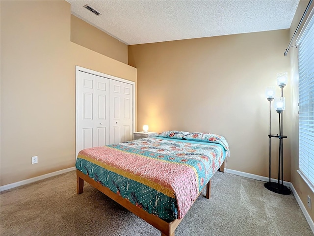 carpeted bedroom with a closet, a textured ceiling, and multiple windows