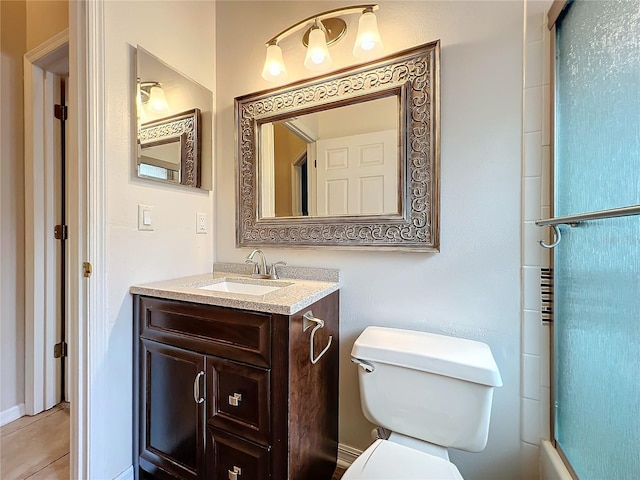 bathroom with toilet, a shower with shower door, and vanity