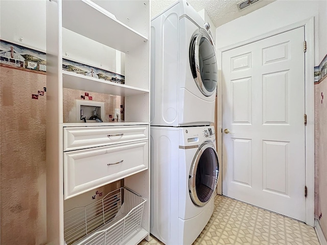 laundry area with a textured ceiling and stacked washing maching and dryer