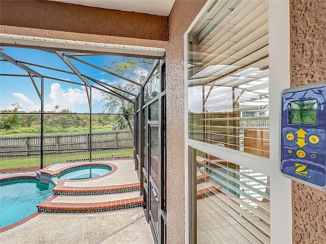 view of pool with an in ground hot tub, a patio, and glass enclosure