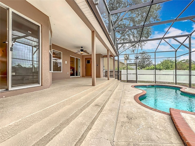 view of swimming pool featuring a patio, glass enclosure, and ceiling fan