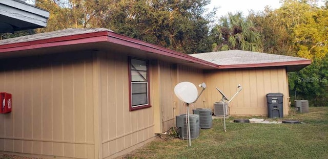 view of side of property featuring central AC unit and a yard