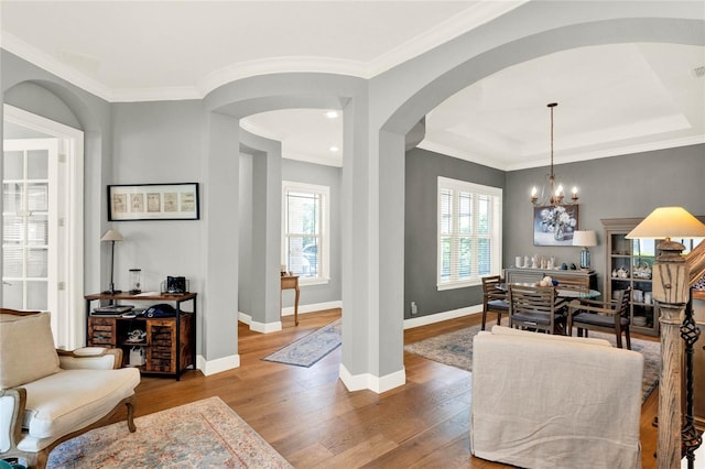 foyer entrance featuring a notable chandelier, ornamental molding, and hardwood / wood-style floors