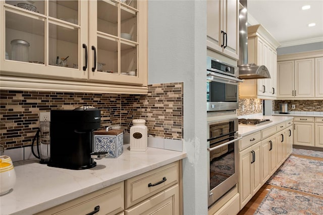 kitchen with appliances with stainless steel finishes, backsplash, light stone countertops, and cream cabinetry