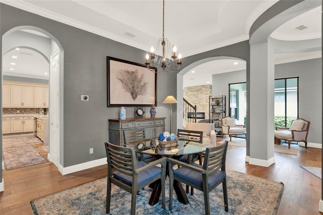 dining space featuring ornamental molding, light wood-type flooring, and a notable chandelier