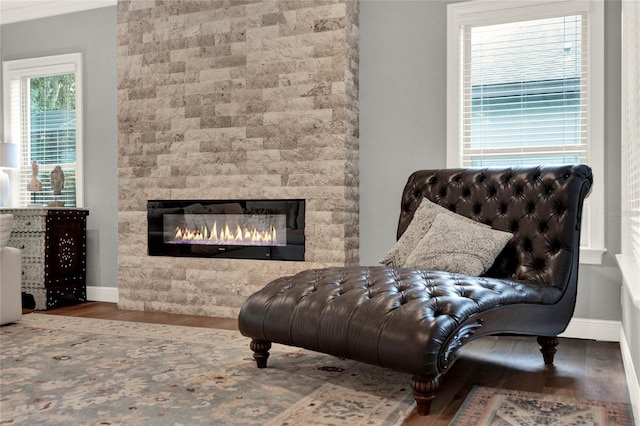 sitting room with a tiled fireplace and hardwood / wood-style flooring