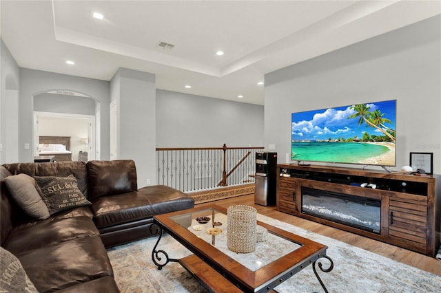 living room featuring a raised ceiling and light hardwood / wood-style floors