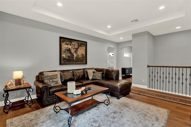 living room with a tray ceiling and hardwood / wood-style flooring