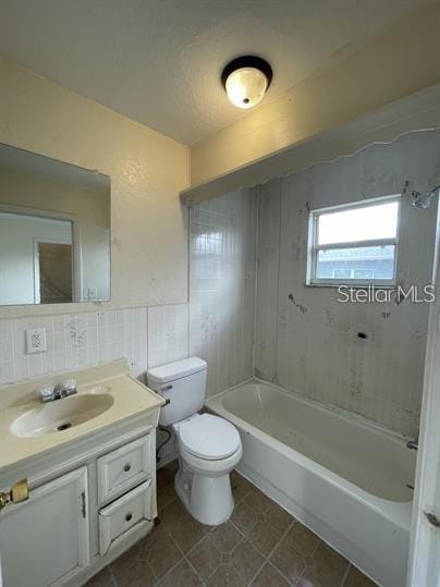 full bathroom featuring tile patterned flooring, decorative backsplash, tiled shower / bath combo, vanity, and toilet
