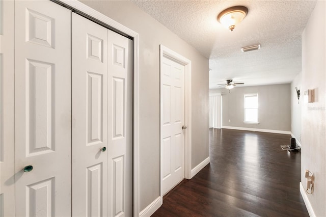 hall featuring a textured ceiling and dark hardwood / wood-style flooring