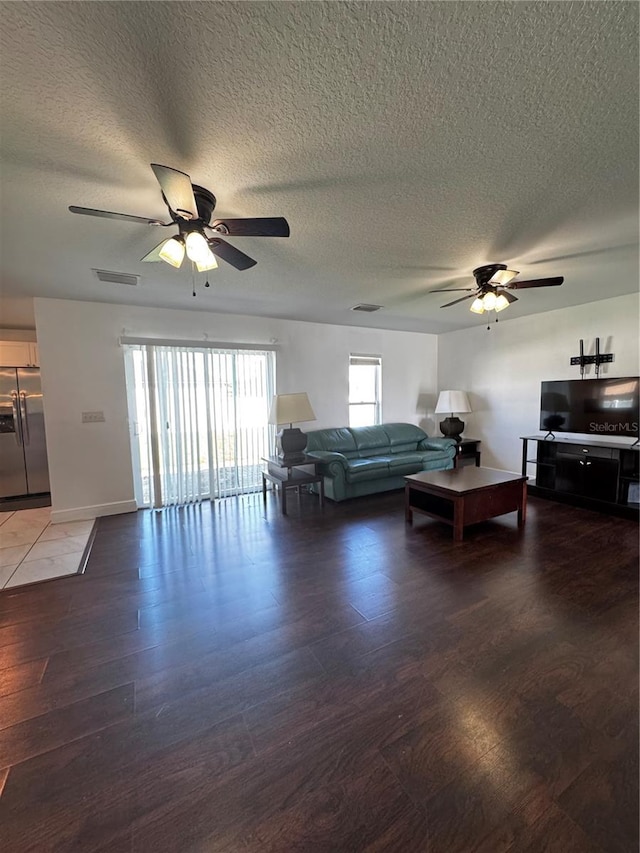 living room with ceiling fan, a textured ceiling, and dark hardwood / wood-style flooring