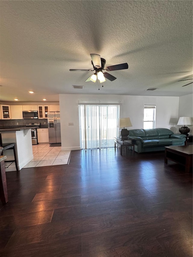 living room featuring a textured ceiling, wood-type flooring, and ceiling fan