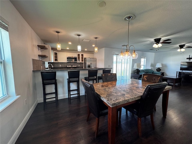 dining space featuring sink, ceiling fan, a textured ceiling, and dark hardwood / wood-style flooring