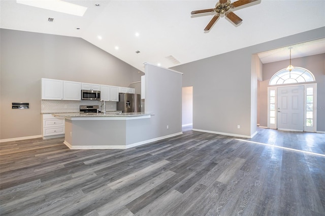 kitchen with ceiling fan, a skylight, dark wood-type flooring, white cabinetry, and stainless steel appliances