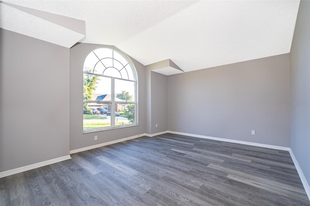 empty room featuring a textured ceiling, lofted ceiling, and dark hardwood / wood-style flooring