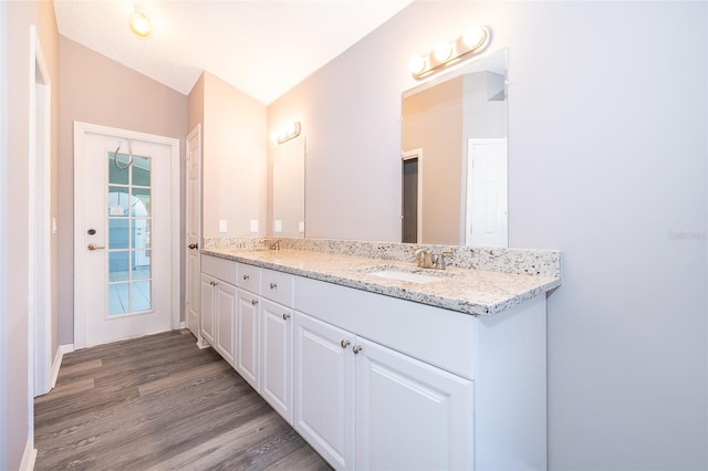 bathroom with wood-type flooring, lofted ceiling, and vanity